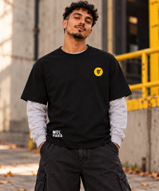 Modelo com t-shirt preta Mel Pirata Powered by Honey, vista de frente, em ambiente urbano.