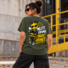 Pessoa com t-shirt verde Mel Pirata, vista de costas, com desenho da abelha Mel e frase Less Drama More Honey.